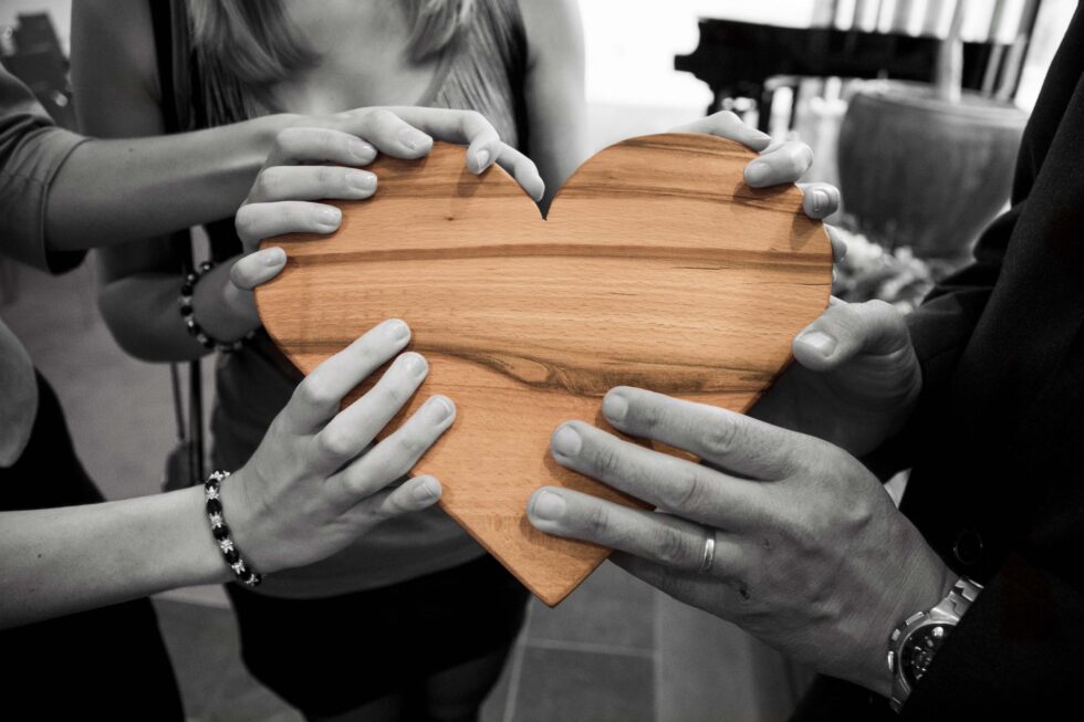 hands holding a carved wood heart